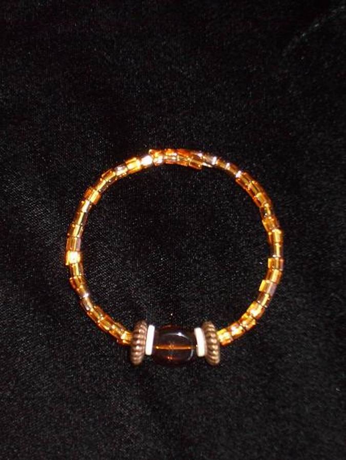 Amber glass beads accented with large brass and ostrich shell beads. Gold memory wire.  (C120P118) - Click for more details