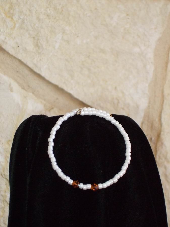 White glass beads accented with two orange Swarovski Crystals. Gold memory wire.  (C120P124) - Click for more details